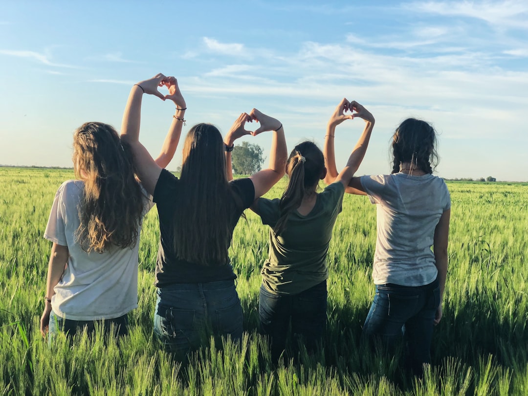 I shot this picture in a breathtaking wheat field in Mexico as the sun was going down. I love how it captures their individaul personalities and who they are as a collective. Together they are facing all the world throws at them. They are each other’s safe harbor. As a mother it blesses my heart to know she has such incredible friend to do life with. by Aquarium Music women forming heart gestures during daytime